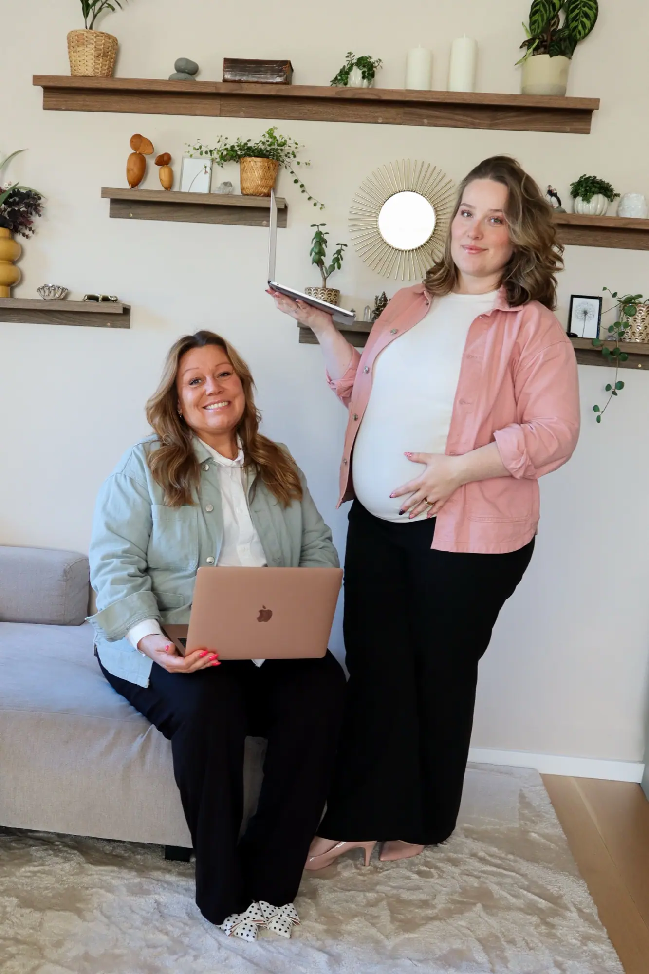Laila sidder med en laptop og Amalie står ved siden af med en tablet
